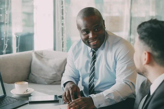 A Black business executive from African Minerals Limited in a meeting, discussing investment and the economic impact of the Tonkolili Iron Ore Project in Sierra Leone.