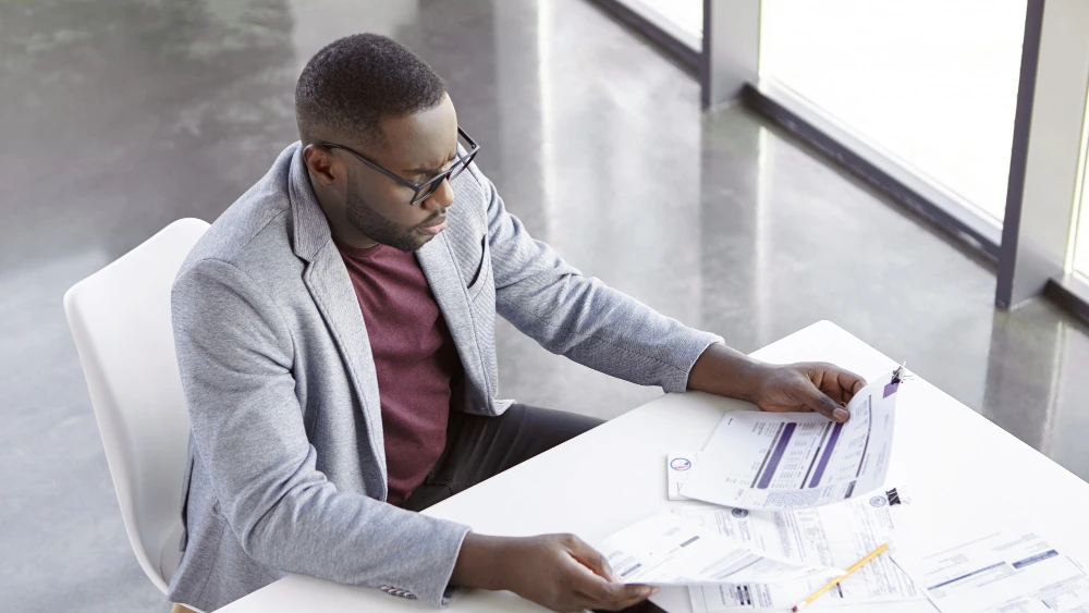 A focused AMML financial analyst reviewing documents and investment reports, representing the company's expertise in the West African finance industry.
