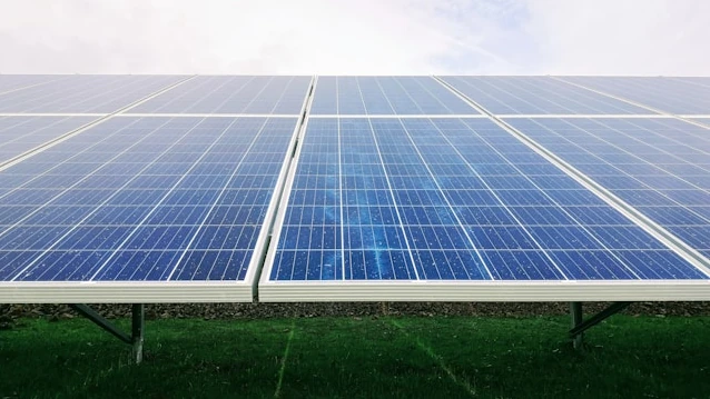 Solar panel array installed in a green field under a clear sky, representing AMML Sierra Leone's investment in renewable energy and other strategic sectors in West Africa.