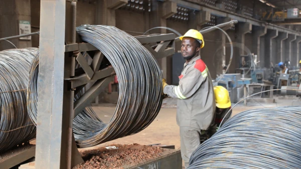 African worker in a factory producing steel rebar coils for the Real Estate and Construction Industry in West Africa, demonstrating AMML's investment in foundational materials.